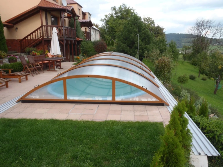 Uzavřená oblouková střecha nad bazénem na terase u rodinného domu.