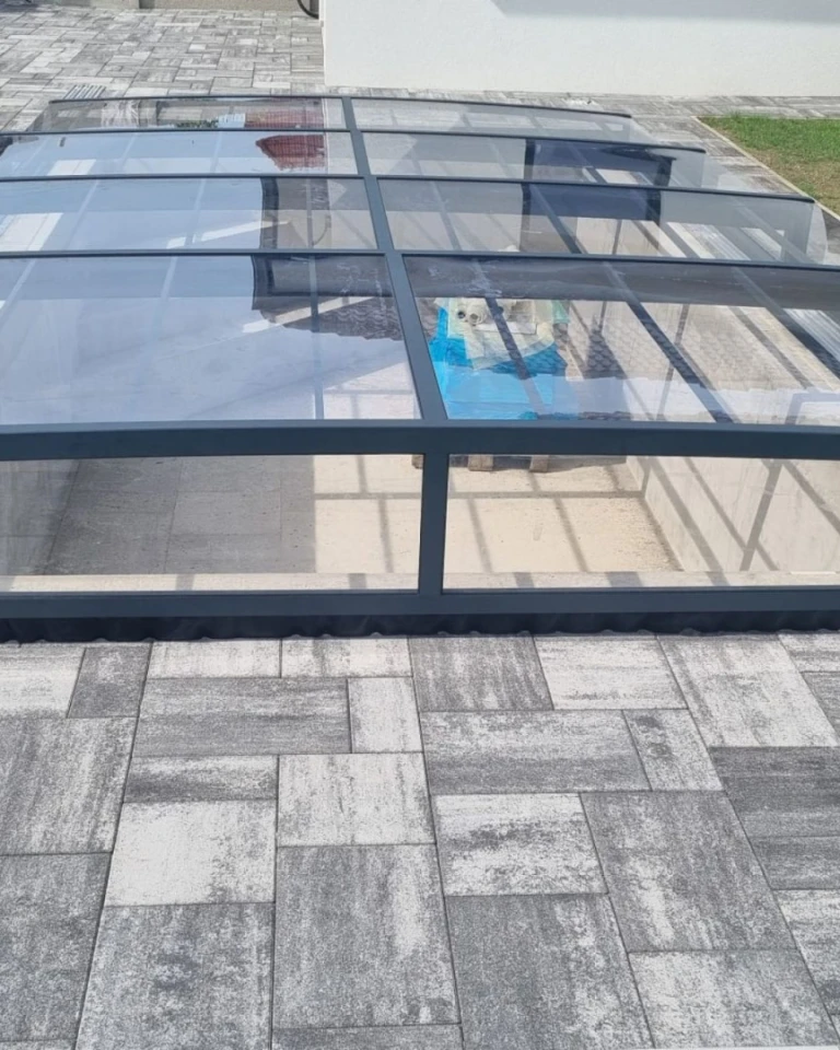 Moderní nízká zastřešení bazénu s antracitovou konstrukcí a čirým polykarbonátem
