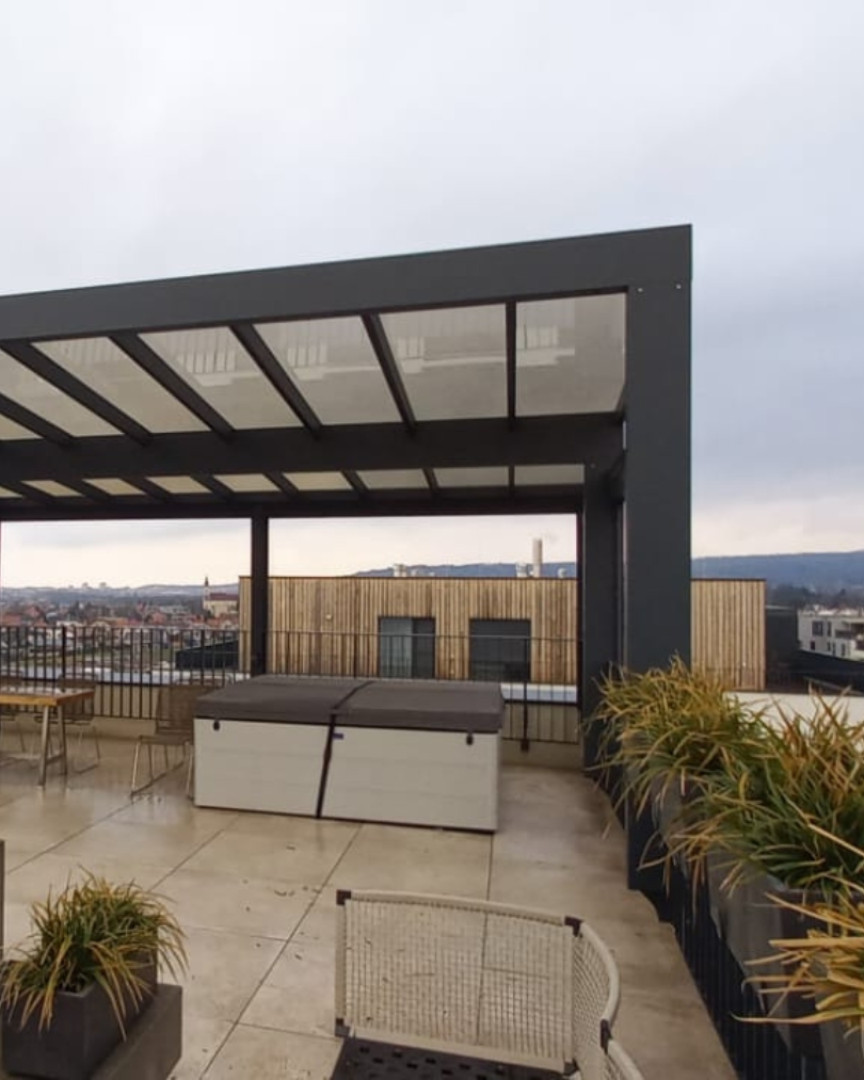 Moderní hliníková pergola na střešní terase s výhledem na město a vířivkou