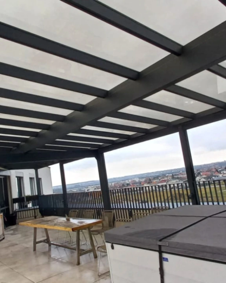 Moderní prosklená hliníková pergola na terase s výhledem na město, stůl a židle