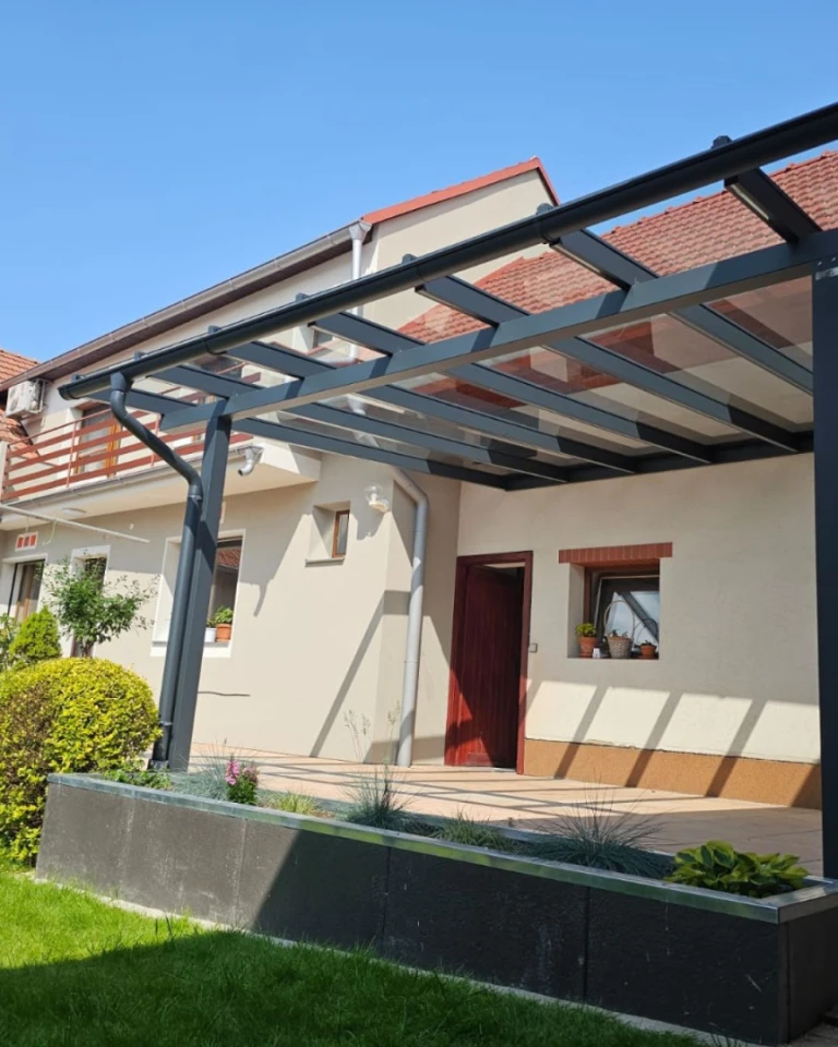Moderní antracitová hliníková pergola se skleněnou střechou přistavěná k rodinnému domu