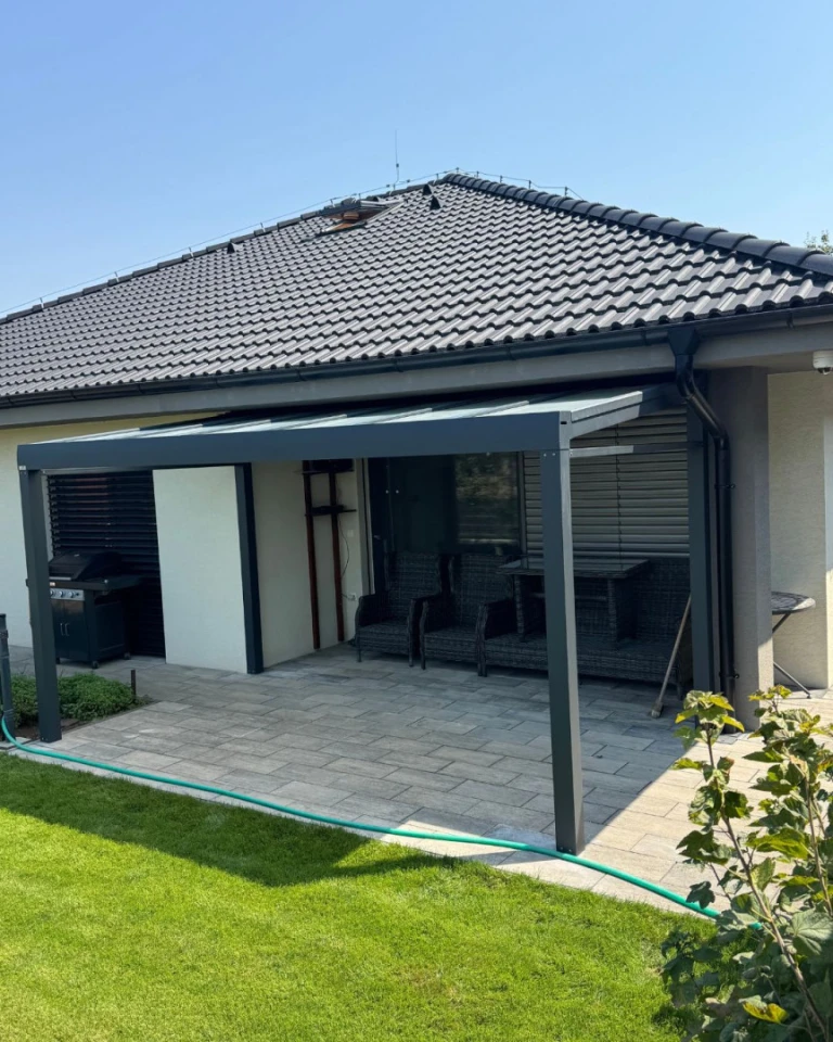 Moderní šedá hliníková pergola Robust na terase rodinného domu s posezením a zahradou