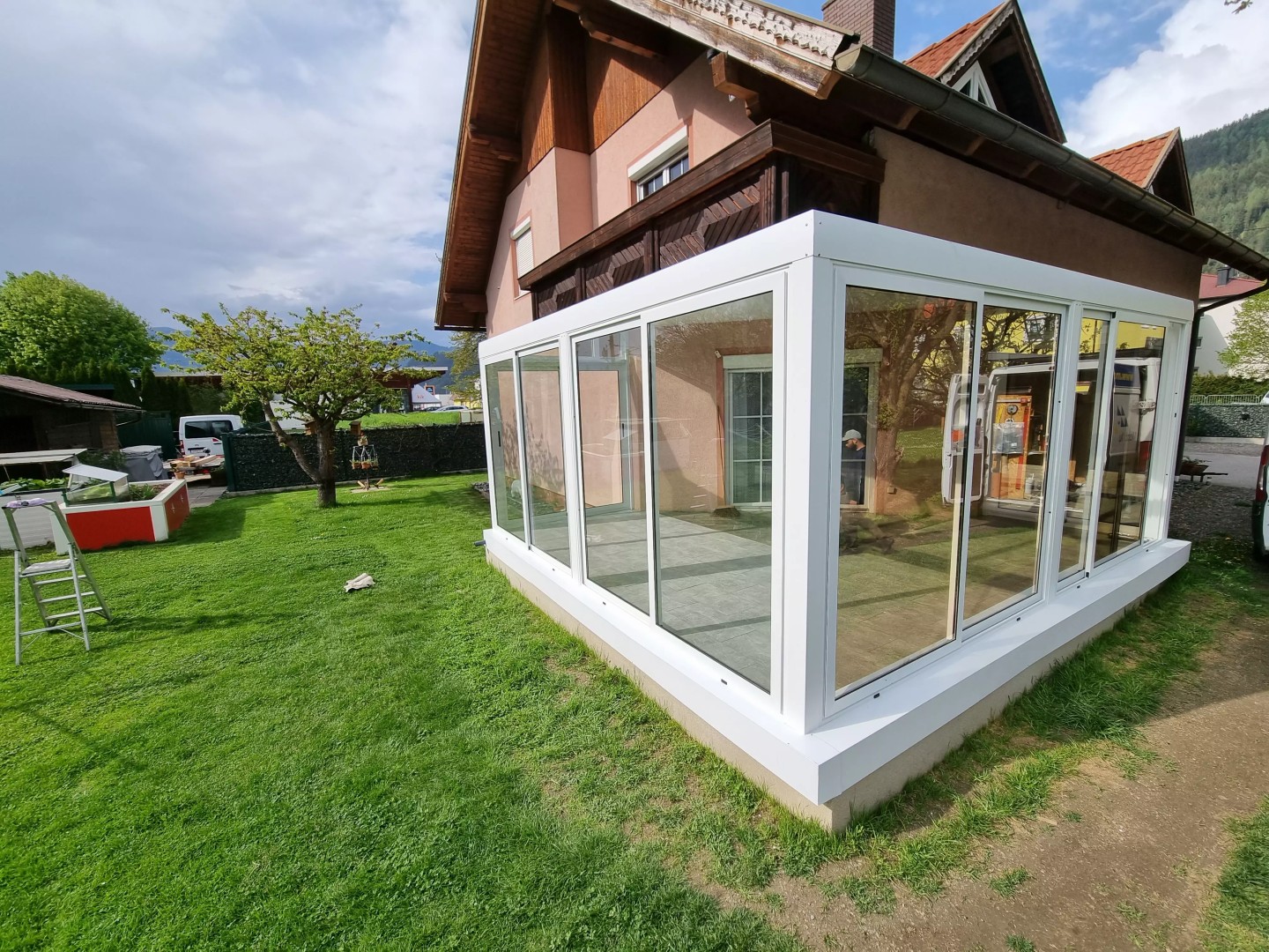 Moderní bílá prosklená hliníková pergola v zahradě u rodinného domu.