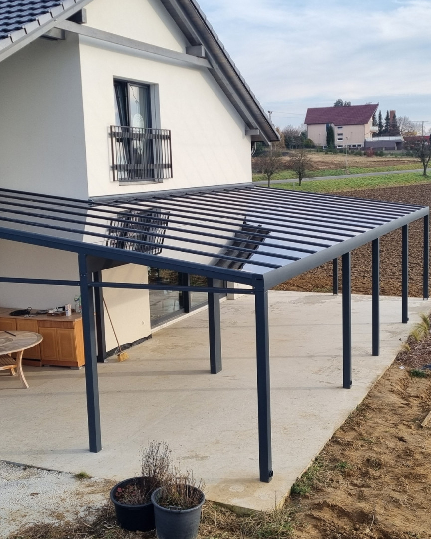 Moderní tmavě šedá hliníková pergola se skleněnou střechou, instalovaná u rodinného domu v Senci.