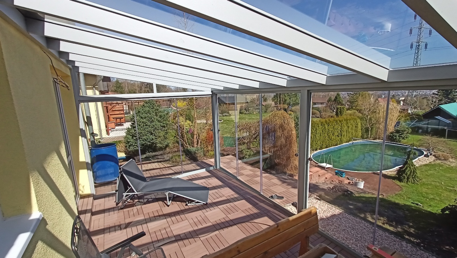 Moderní prosklená hliníková pergola s terasou a výhledem do zahrady s bazénem