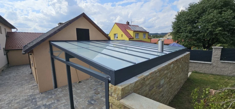 Moderní zastřešení terasy s antracitovou hliníkovou konstrukcí a skleněnou střechou u rodinného domu
