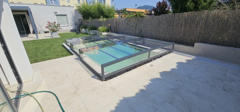 Moderní nízká krytina bazénu EXCLUSIVE s tmavým rámem a čirým výplňovým materiálem na terase rodinného domu