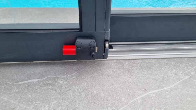 Detail uzamykacího mechanismu hliníkového krytu bazénu s červenou pojistkou